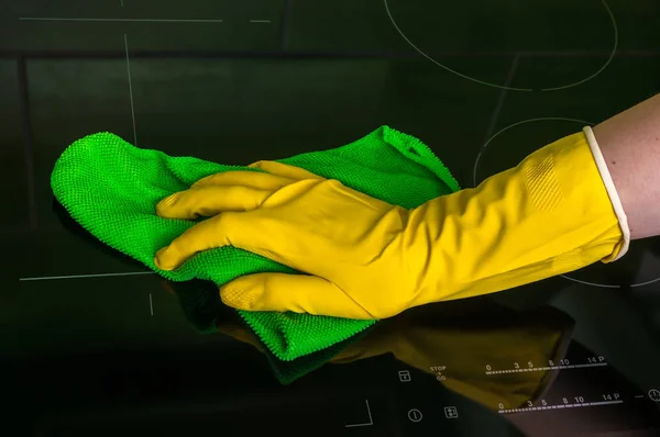 Mão na luva com pano verde está limpando placas de indução — Fotografia de Stock