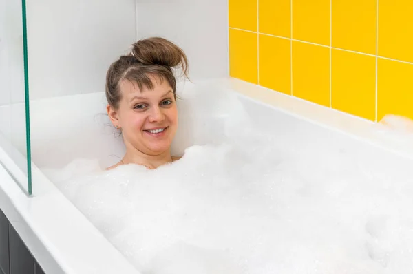 Hermosa mujer joven está tomando un baño relajante con espuma —  Fotos de Stock