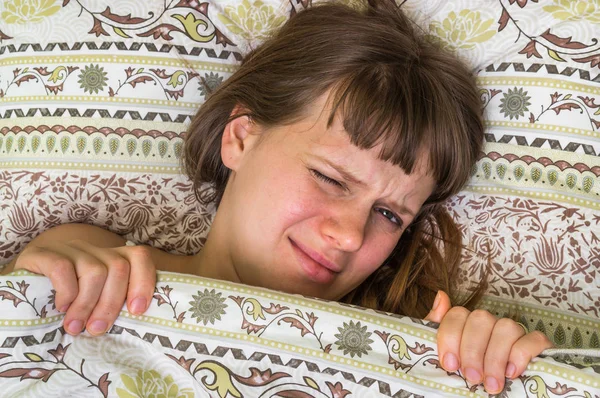 Mujer joven en la cama con dolor de cabeza en la mañana — Foto de Stock