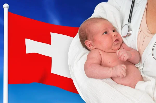 Birth rate in Switzerland. Newborn baby in hands of doctor.