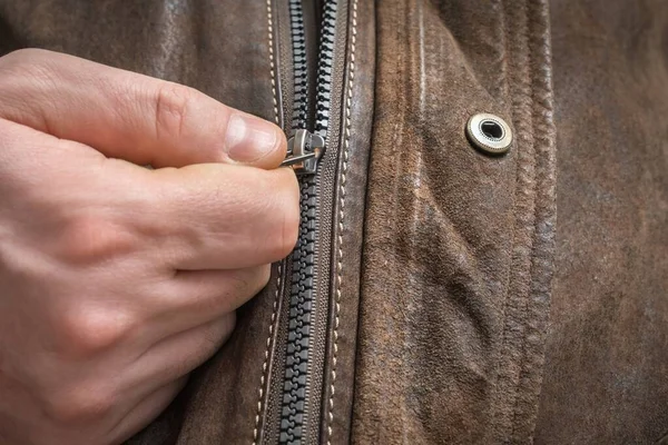 Man in modern leather jacket is fastening zipper
