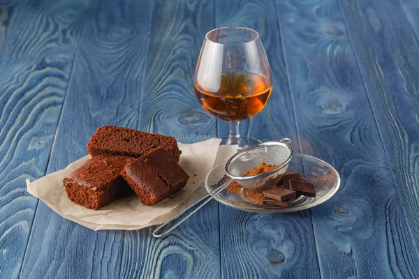 Glas Rum auf Holztablett mit Schokoladenbrownies im Rücken — Stockfoto