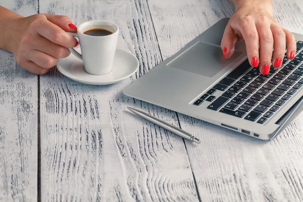 En dam håller kaffe i handen på det Pc-skrivbordet. — Stockfoto