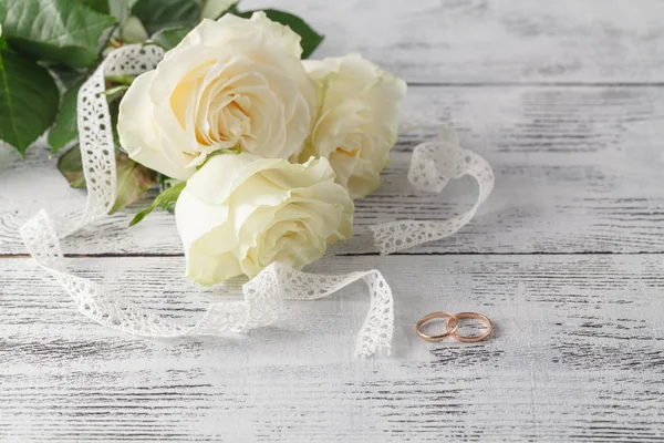Anéis de casamento de ouro em um buquê de rosas brancas — Fotografia de Stock