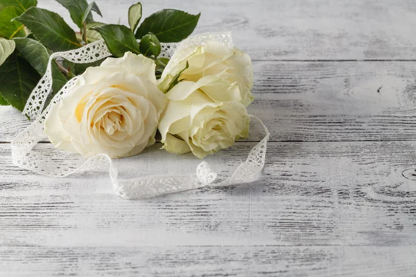 Білі свіжі квіти троянд на білому мереживному фоні — стокове фото