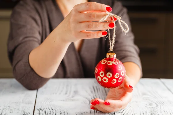 Chica sosteniendo la bola de Navidad en los dedos. Hermosa manicura en un — Foto de Stock
