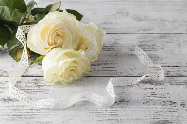Букет з білих троянд, прикрашений стрічкою на білому дерев'яному спині — стокове фото
