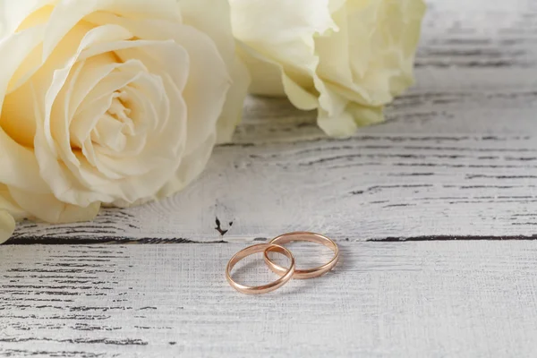 Detailní záběr snubních prstenů na pozadí růží — Stock fotografie
