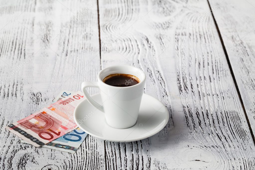 euro bill and cup of coffee on wooden table. Payment, tip.