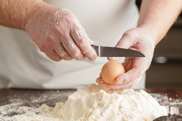 Dwie ręce break jajko na powierzchni drewnianych na sterty mąki — Zdjęcie stockowe