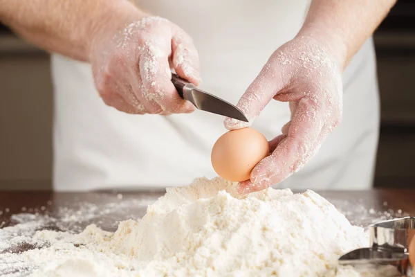 Homem quebra ovo acima da farinha branca para fazer massa para ravioli ou du — Fotografia de Stock