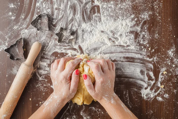 Mãos da mulher amassar massa na mesa de madeira — Fotografia de Stock