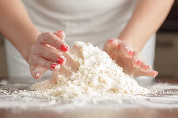 Mani di donna impastando la pasta su tavolo di legno — Foto Stock