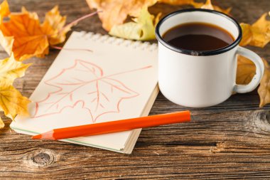 Kitap yazma, bir fincan ve sonbahar yaprakları çok renkli kalemler