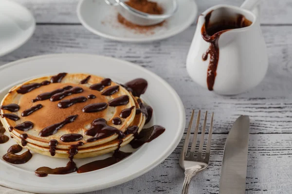 Stapel leckerer Pfannkuchen mit Schokolade auf Teller und Serviette o — Stockfoto