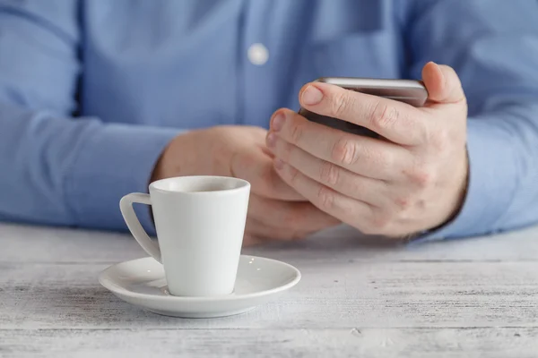 Az ember ül a smartphone-on kávé asztal — Stock Fotó