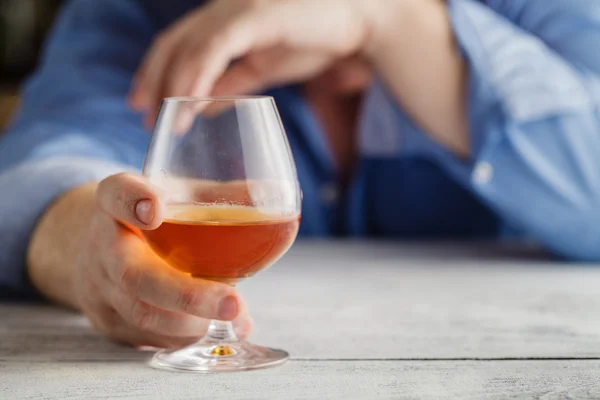 Alkoholos ember alszik a tábla. Üveg alkohollal a kezében. — Stock Fotó