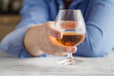 bir bardak portakal alkol içkiyle geri tutan adamın eli kirli