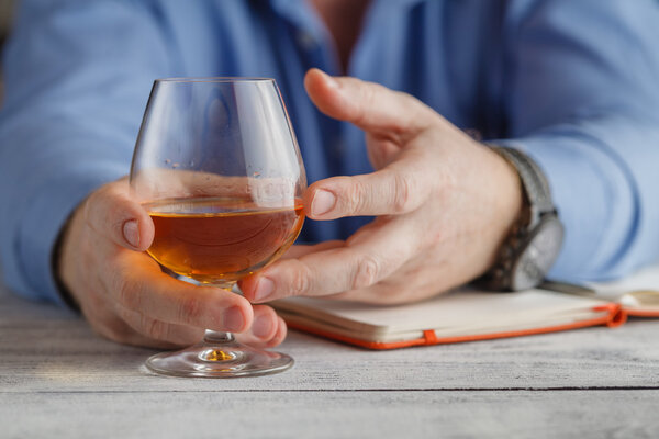 Концепция релаксации - стакан бренди в мужских руках. Селективный
 