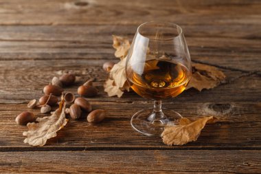 snifter of brandy and dried oak leaves`