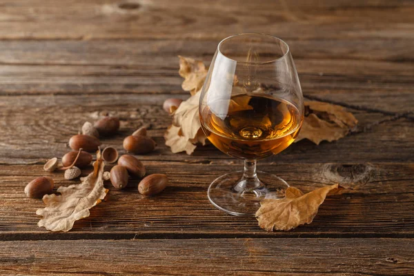 snifter of brandy and dried oak leaves`