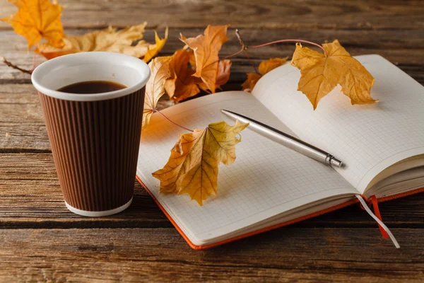 Tazza di tè con vecchio libro, foglie autunnali sul tavolo di legno Foto Stock