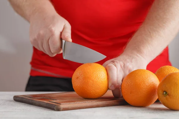 Corte de pessoa para fazer suco de laranjas frescas na mesa de madeira — Fotografia de Stock