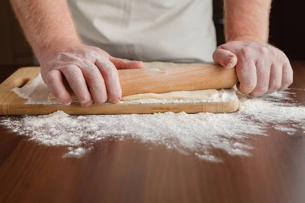 As mãos de homens estendem a massa de farinha de perto. Homem preparando massa para cooki — Fotografia de Stock