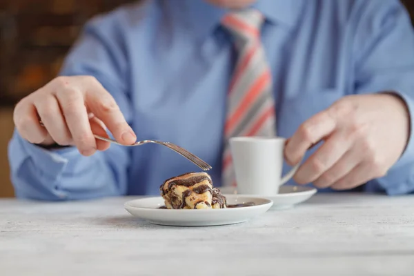 Man eating strawberry cheesecake in cafe drinking coffee