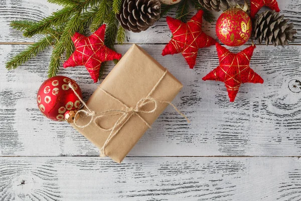 Beyaz ahşap zemin üzerinde kırmızı topları fiyonklu Noel hediye