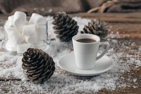 Чашка с горячим кофе, стоящим на снегу с желтыми листьями. На открытом воздухе — стоковое фото