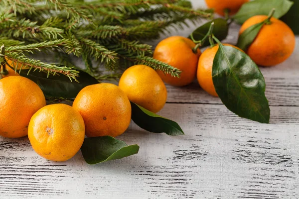 Fir branch and tangerines on the old wooden background — Stock Photo, Image