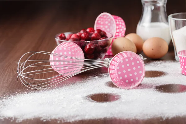 Muffin ingredients: the frozen cherry in a plate, eggs, flour on