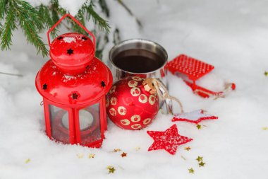 Eski kupa ve köknar koni içinde karda sıcak bir içecek ile 