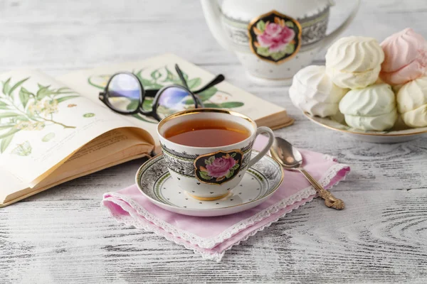 Чашка чая, книга на деревянном столе — стоковое фото