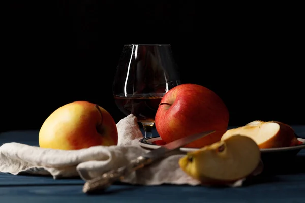 Sklo s calvadosem brandy a žlutého jablka na dřevěný stůl — Stock fotografie