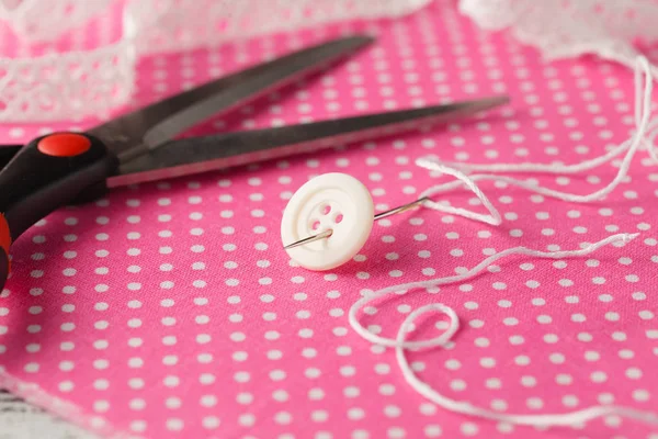 Aiguille et bouton sur tissu à pois rose — Photo