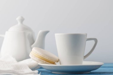 Beyaz parcelain fincan çay ve bir acıbadem kurabiyesi