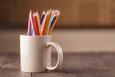 ahşap masa üstünde mug içinde birçok kalemler