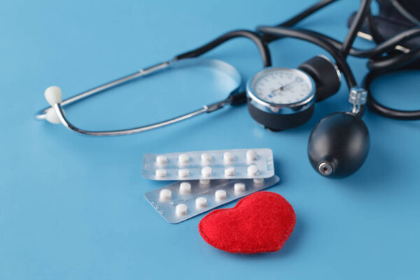Концепция здравоохранения сердца, тонометр и игрушечное сердце на голубом фоне

