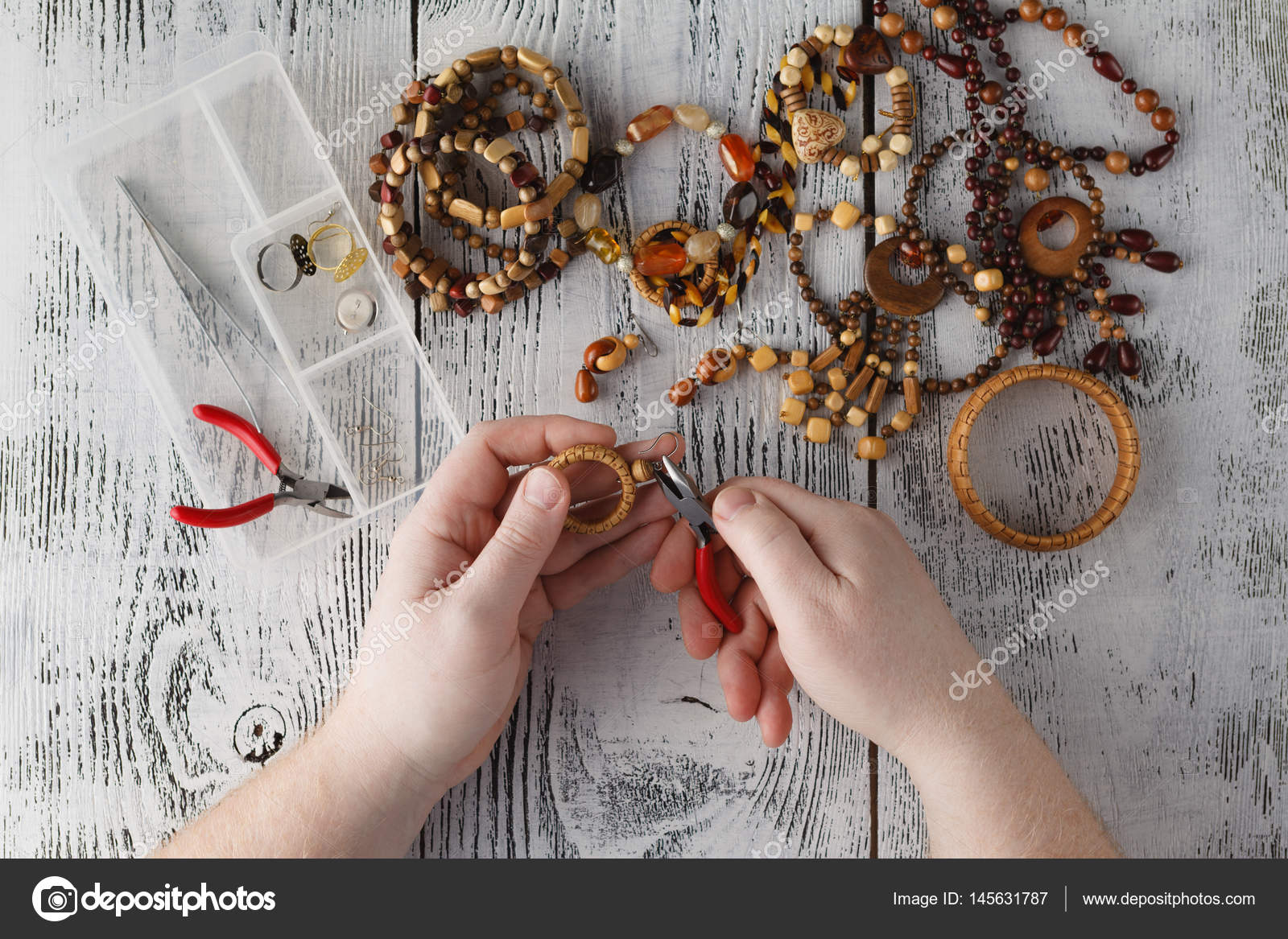Man making handmade jewelry. Boxes with beads accessories for n