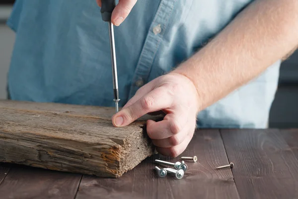 Die Hand eines Mannes mit einem Schraubenzieher, der Holzplanken zusammenschraubt — Stockfoto