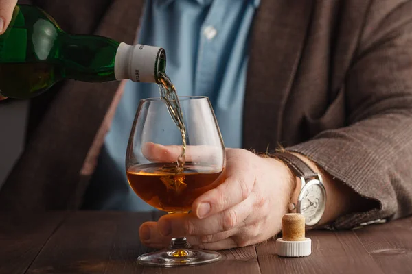 Człowiek sobie kurtkę trzymając szklankę whisky w barze licznik — Zdjęcie stockowe