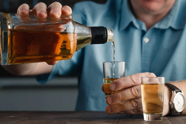 Один білий чоловік крупним планом наливає алкоголь у склянку — стокове фото