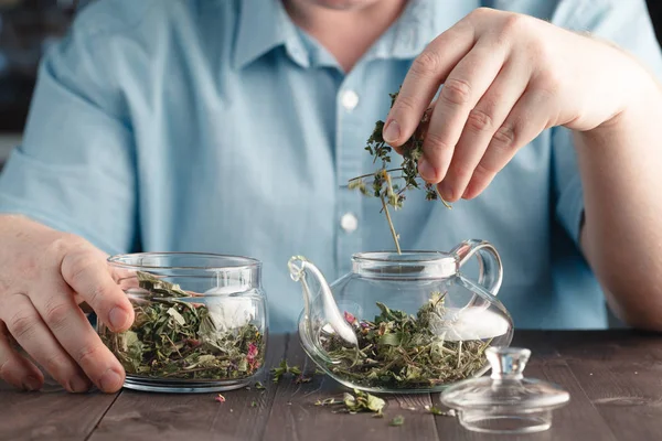 Male hands Puts herbal tea in the kettle — Stock Photo, Image