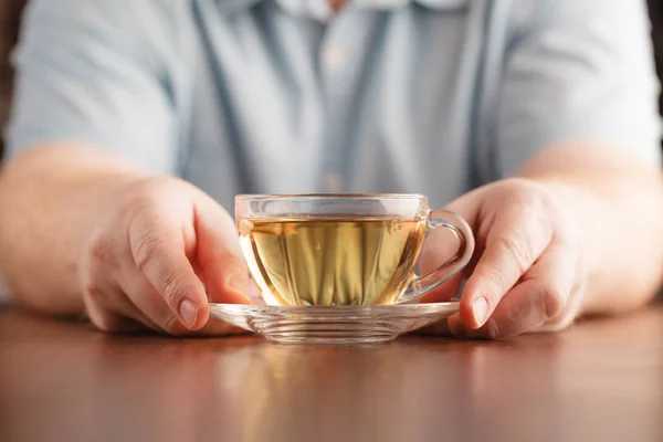 男の手にカップを保持し、お茶を提供 — ストック写真