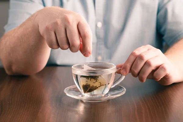Чоловік заварює чайний мішок зі склянкою чаю на столі в офісі — стокове фото
