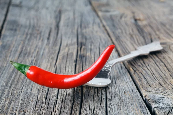 Un piment rouge à la fourchette posé sur une table rustique — Photo