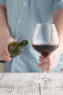 bir bardak kırmızı şarap ve şişe tutan adam