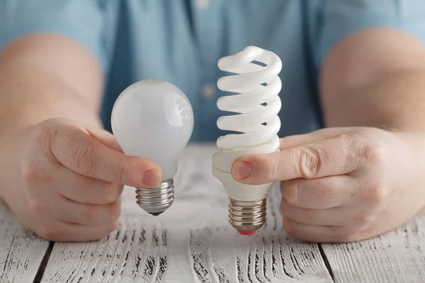 Man hold Normal and Saver Lightbulb